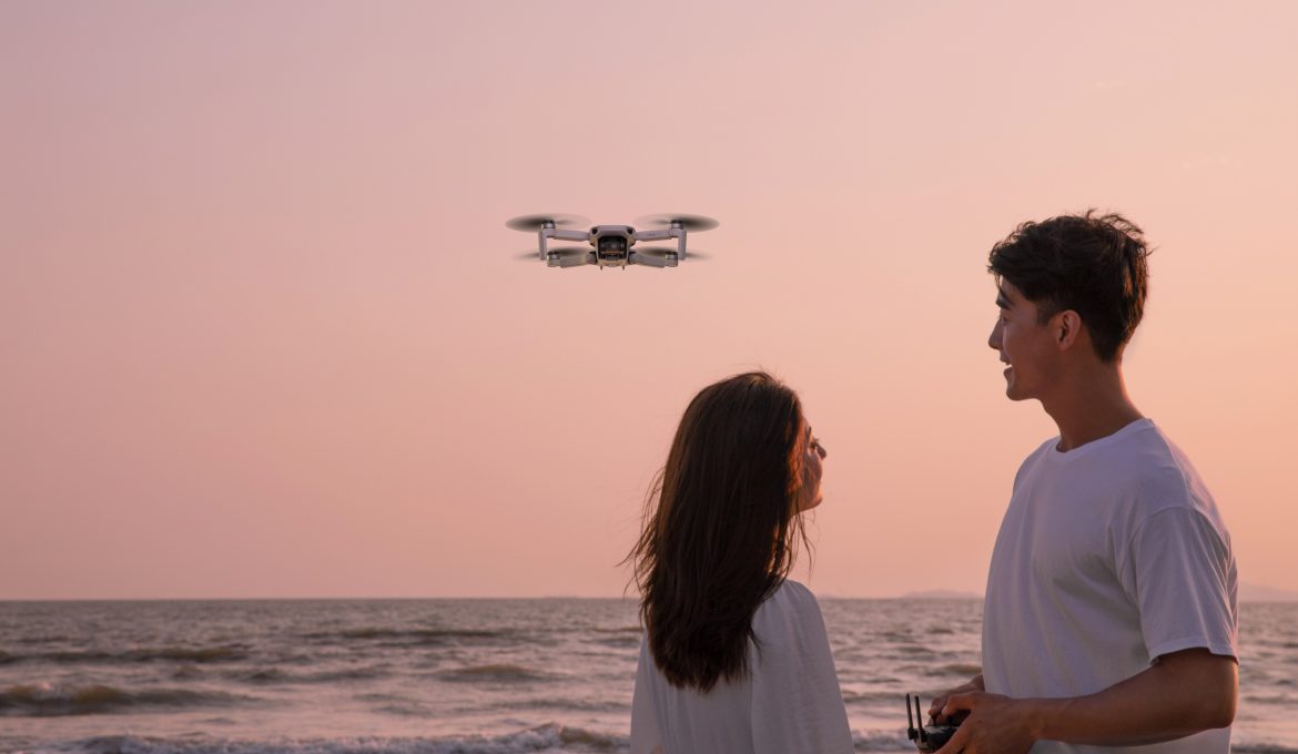 Pärchen fliegt DJI Mini Drohne am Strand