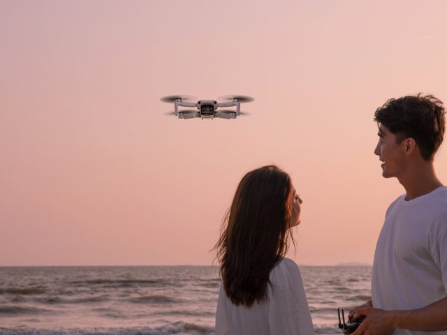 Pärchen fliegt DJI Mini Drohne am Strand