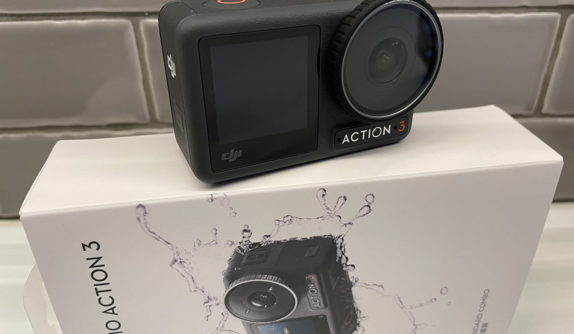 DJI Osmo Action 3 Kamera auf quergestelltem Originalkarton vor grauen Fliesen und weißem Untergrund