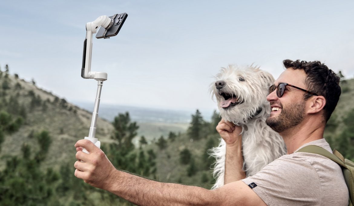 Mann mit Hund macht Selfie mit Smartphonegimbal von Insta360 vor Berglandschaft