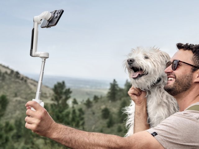 Mann mit Hund macht Selfie mit Smartphonegimbal von Insta360 vor Berglandschaft