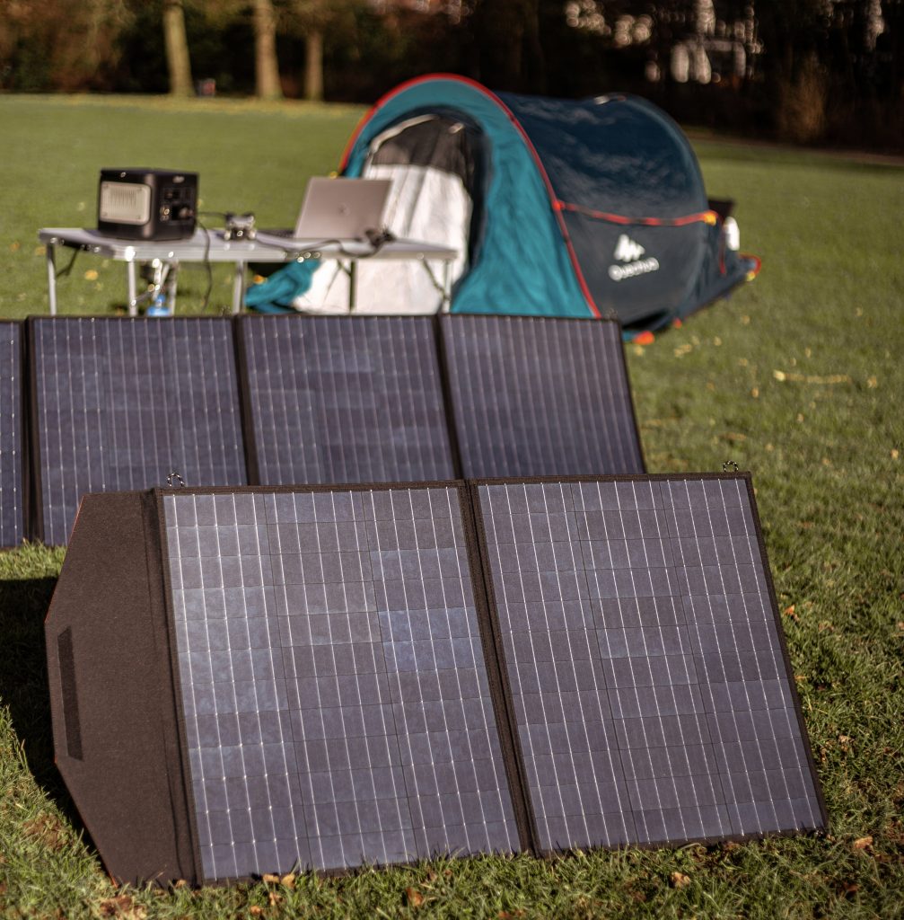 Rollei Solarpanel vor Camping-Kulisse auf grüner Wiese