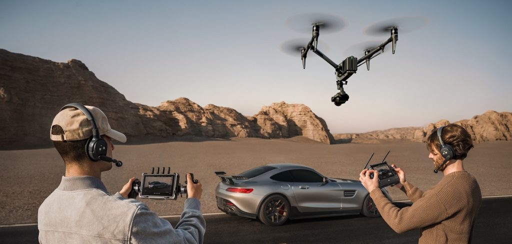 Zwei Männer steuern DJI Inspire 3 Drohne über Auto in Wüstenlandschaft