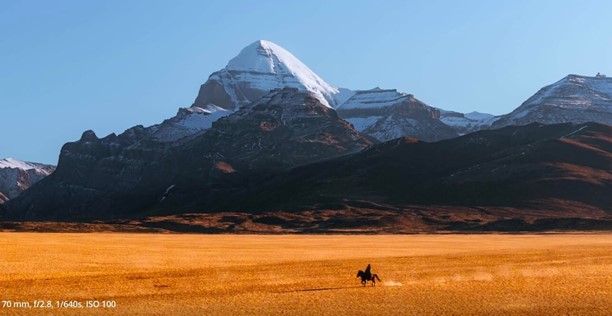 Reiter in Prärie vor Berglandschaft mit verschneiten Gipfeln
