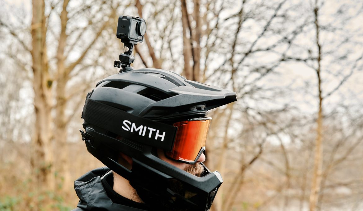 MTBer mit Vollvisier-Helm und Actioncam auf dem Helm vor Waldhintergrund