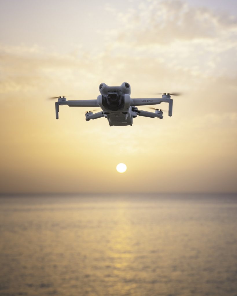 DJI Mini 4 Pro schwebt über dem Meer vor Sonnenuntergang