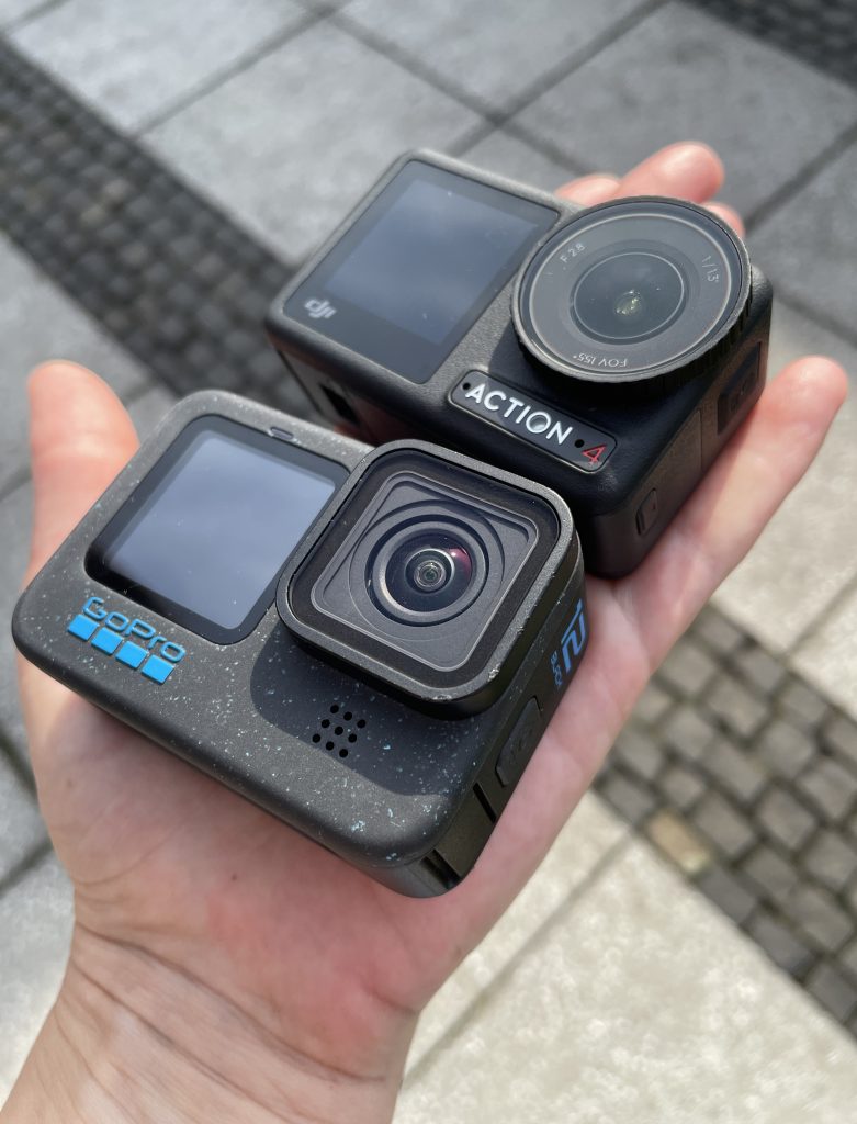 GoPro HERO12 und DJI Osmo Action 4 auf Handteller über Betonplatten