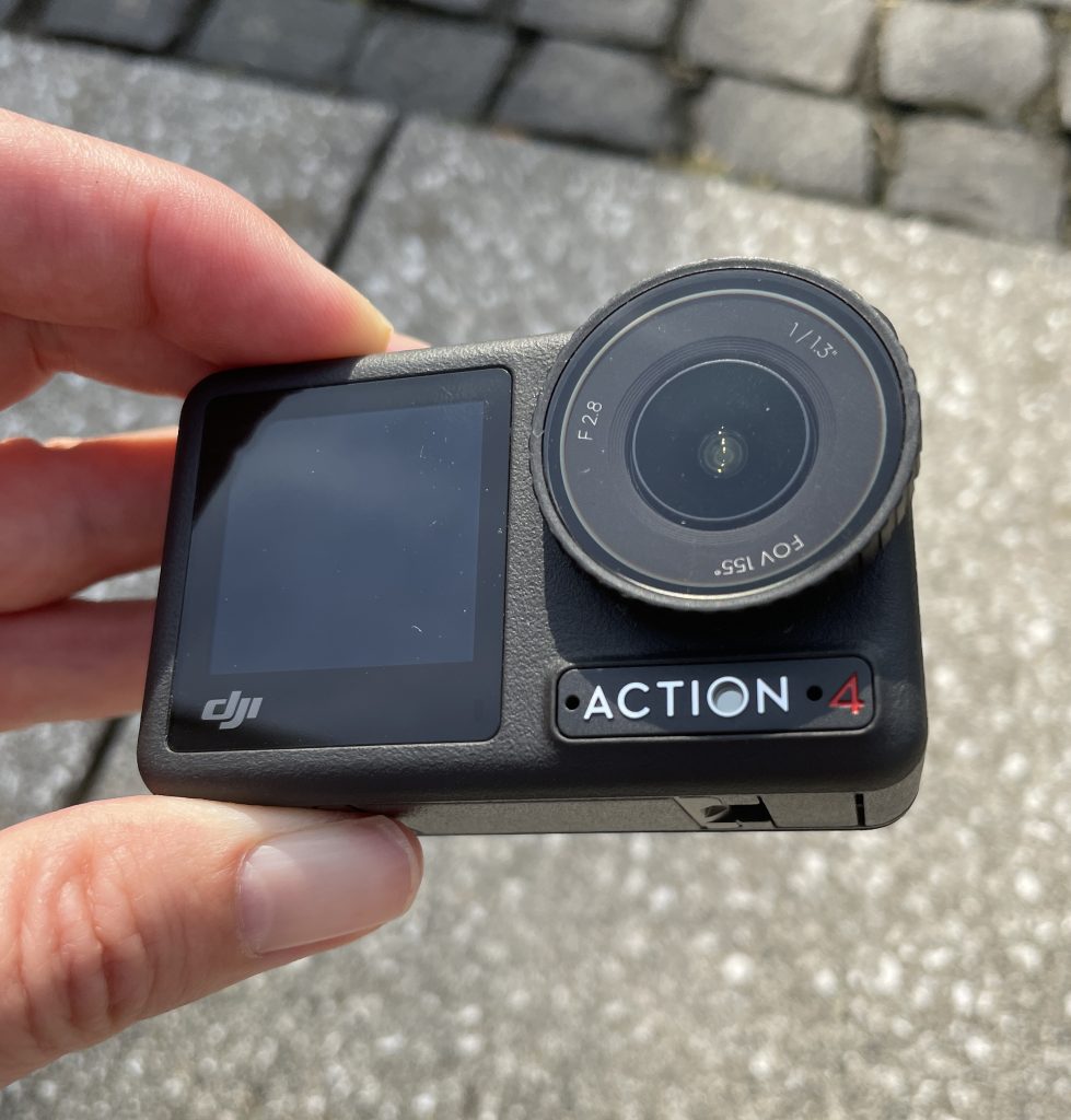 Finger halten DJI Osmo Action 4 über Pflasterseinen