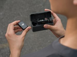 Mann hält DJI Mic 2 Mikrofonsystem mit Ladeschale in den Händen