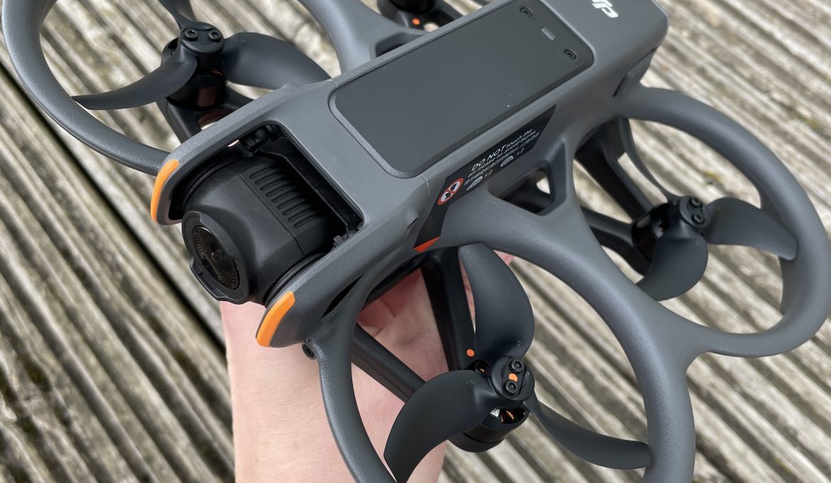 Hand hält DJI Avata 2 Drohne über Holzboden