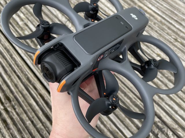 Hand hält DJI Avata 2 Drohne über Holzboden