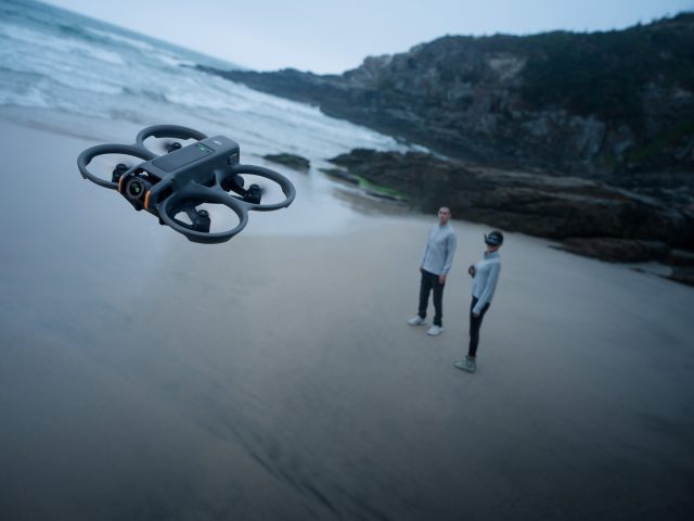 DJI Avata 2 Drohne schwebt über Strand mit zwei Menschen