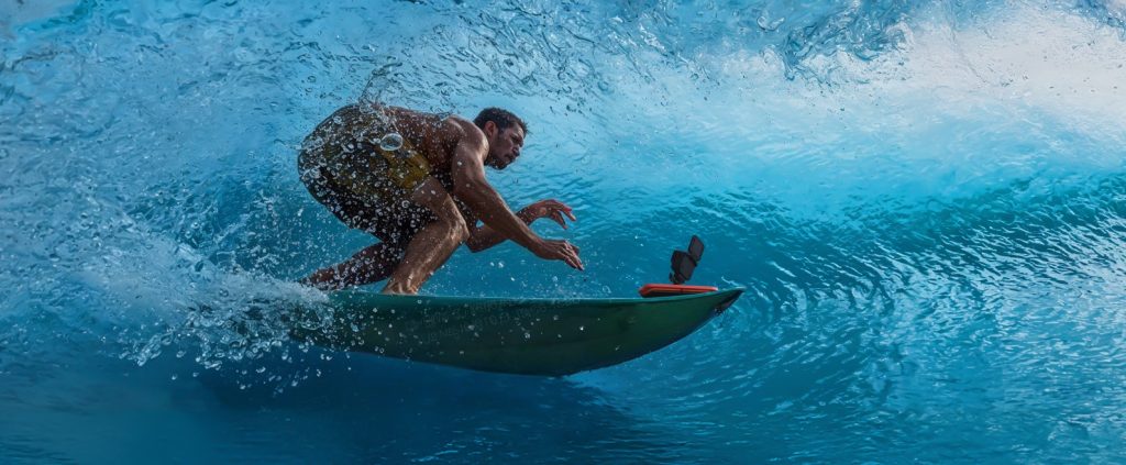 Surfer in einer Welle mit Actioncam auf dem Brett