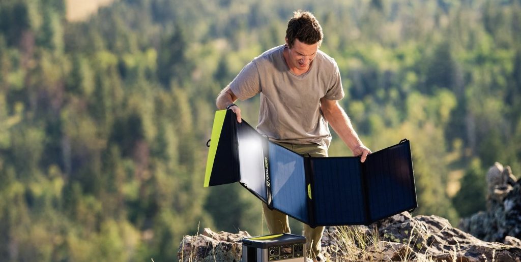 Mann breitet Solarpanel auf sonniger Lichtung aus